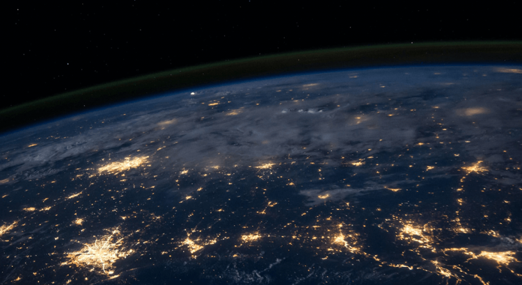 Widok z kosmosu na półkulę Ziemi ogarniętą nocą. Widoczne gdzieniegdzie duże skupiska świateł w miastach