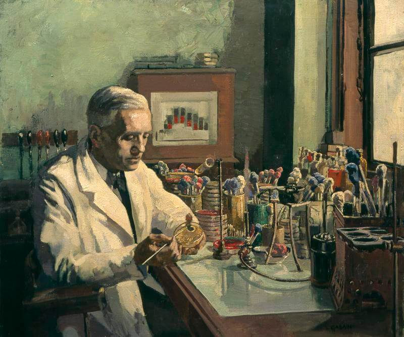 Alexander Fleming w swoim gabinecie przy biurku pełłbym narzędzi chemicznych
