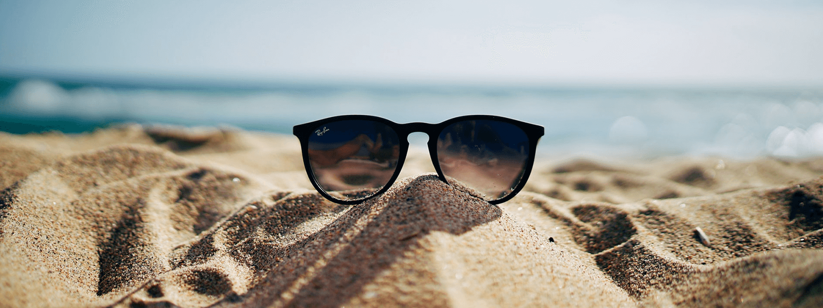 okulary przeciwsłoneczne leżące na piasku nad morzem